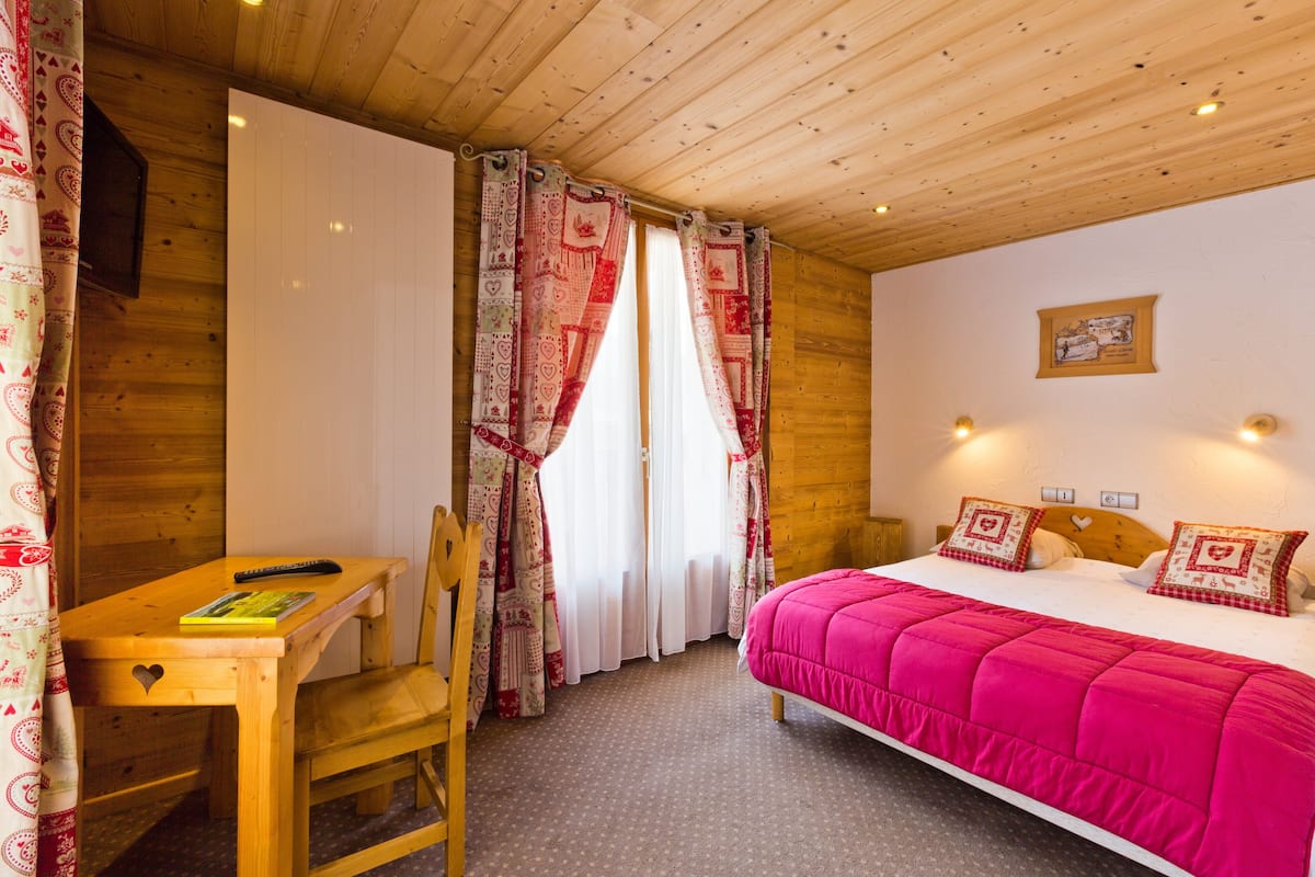 A wooden room with a bed, a desk, and a chair.