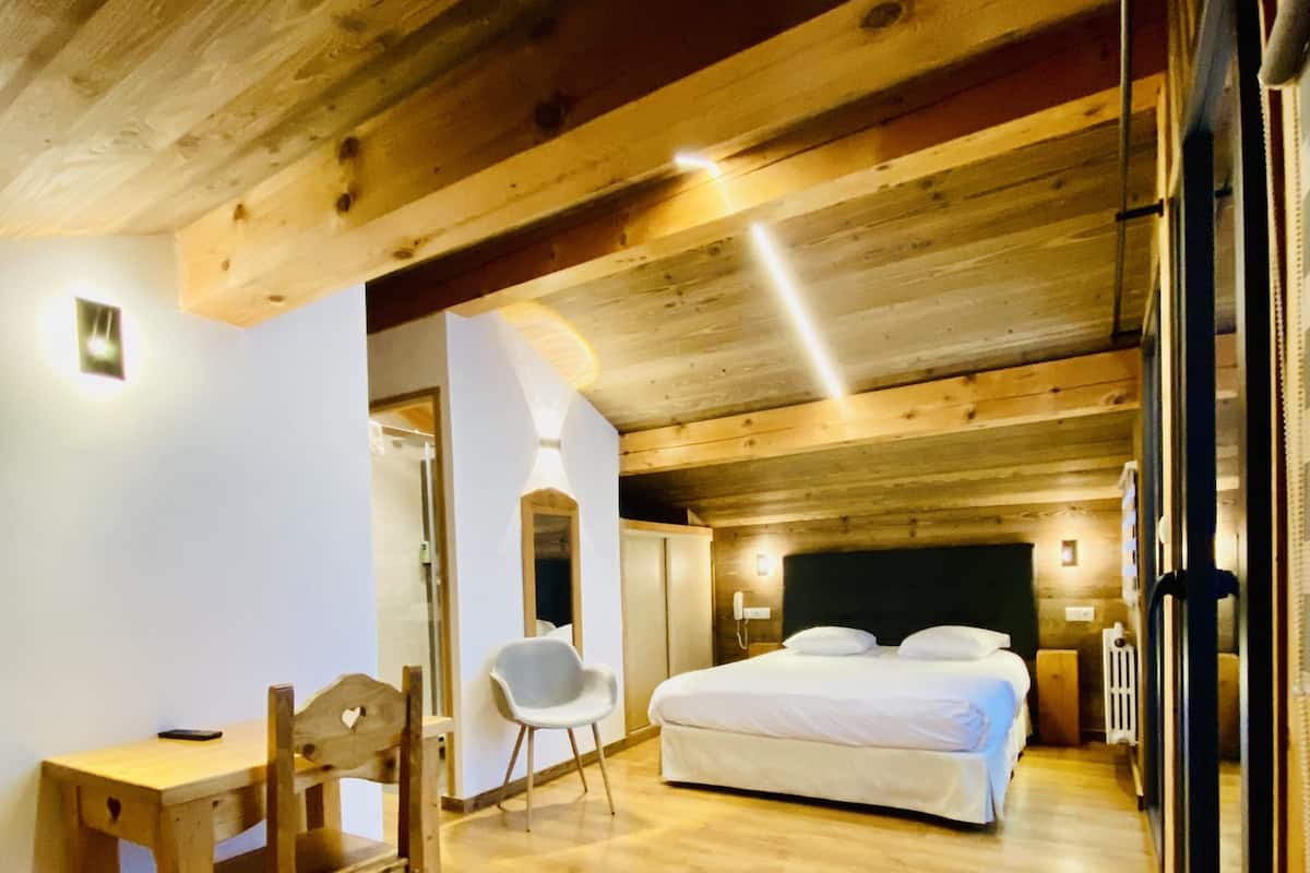 A wooden interior with a bed, a desk, and a chair.