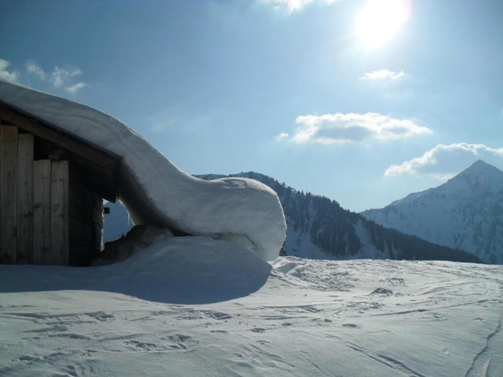 A snow-covered landscape with a wooden structure partially buried in snow.