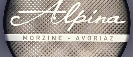 A circular sign with the text "Alpina MORZINE - AOVORIAZ" on a textured background.
