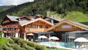 Un hotel de estilo chalé con varias edificaciones de madera, una piscina y asientos al aire libre.