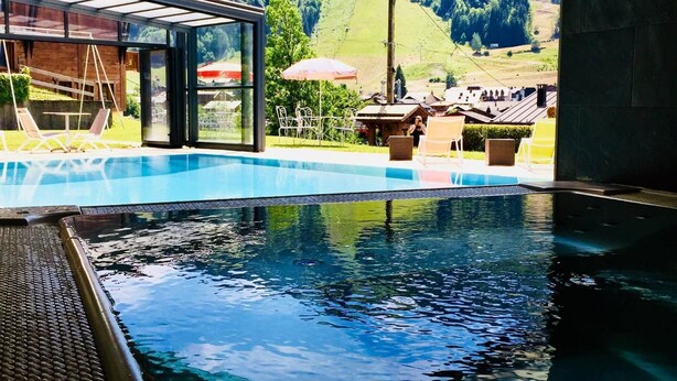 Una piscina con agua cristalina, rodeada de mobiliario exterior y vistas a un paisaje montañoso.
