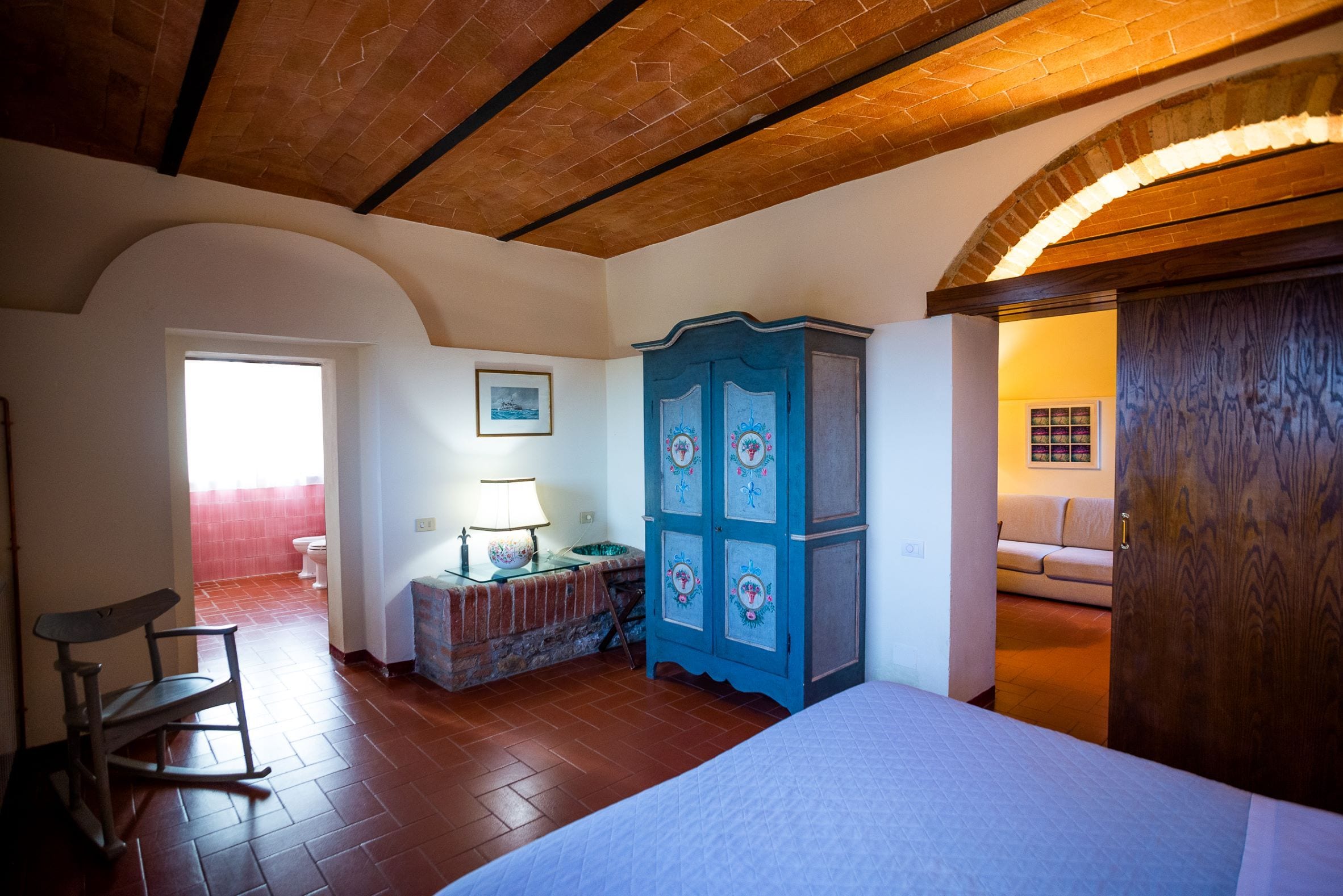 Een slaapkamer met een bed, een dressoir, een stoel en uitzicht op de badkamer.