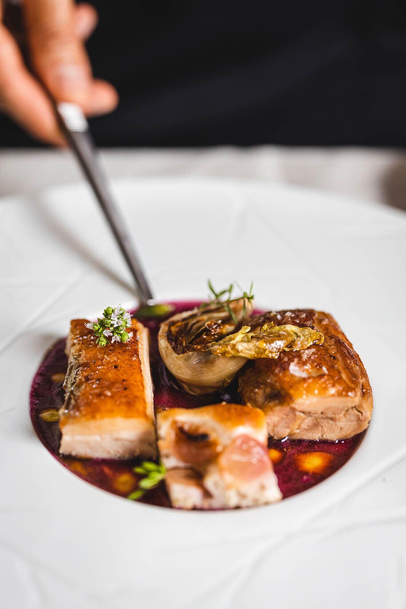 A plated dish with meat and vegetables, garnished with herbs.