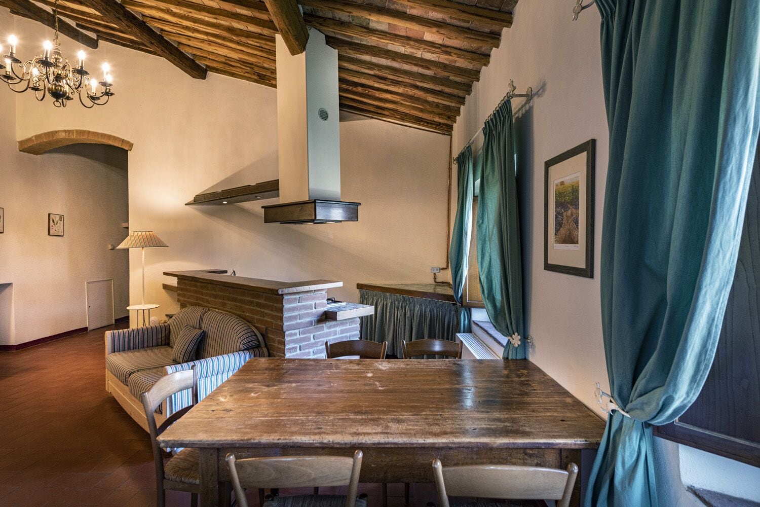 Un rincón comedor acogedor con una mesa y sillas de madera, una chimenea de ladrillo y una lámpara colgante.