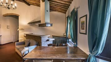Un rincón comedor acogedor con una mesa y sillas de madera, una chimenea de ladrillo y una lámpara colgante.