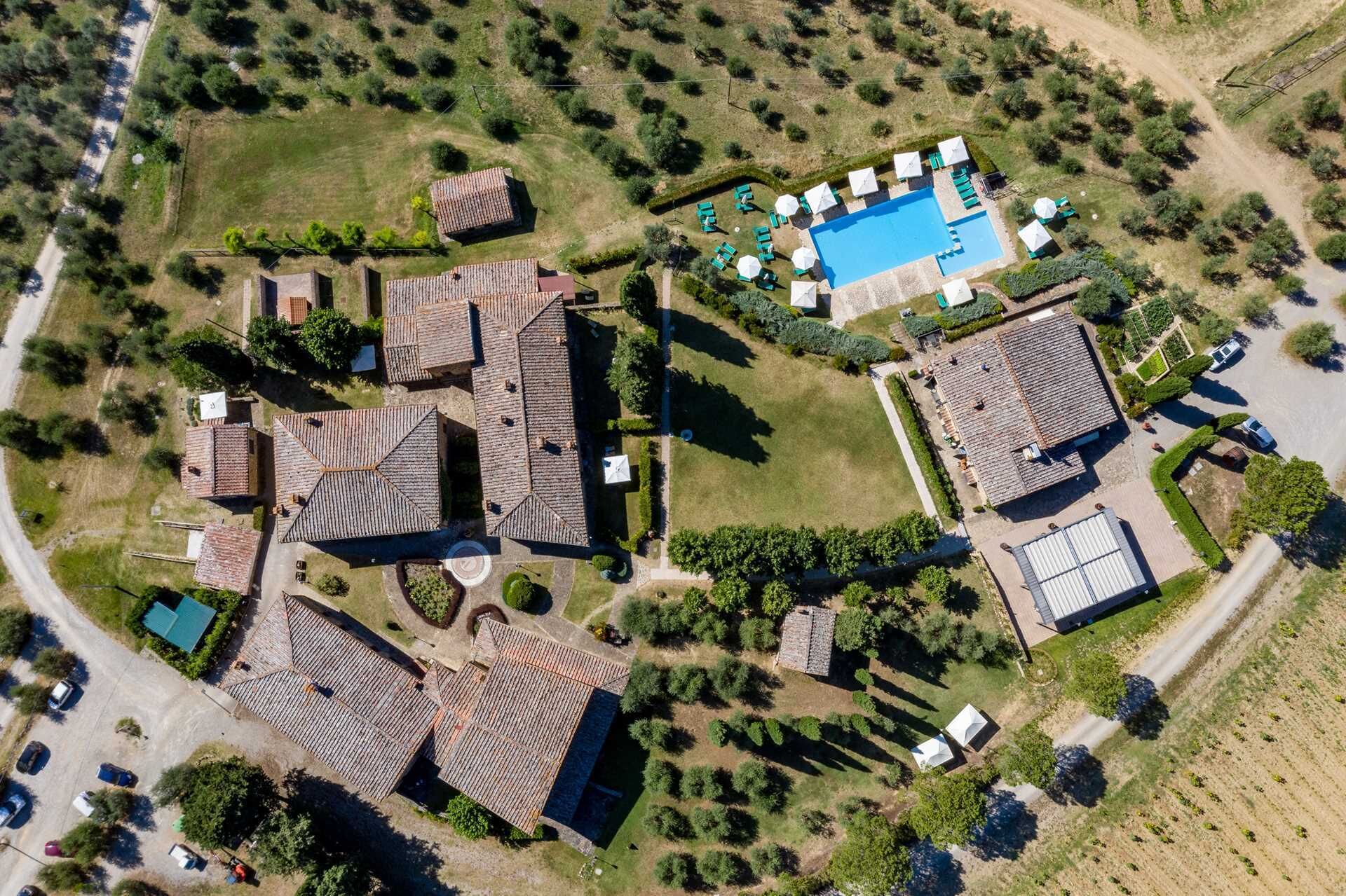 Vista aèria d'una propietat amb diversos edificis, una piscina i una zona d'aparcament.