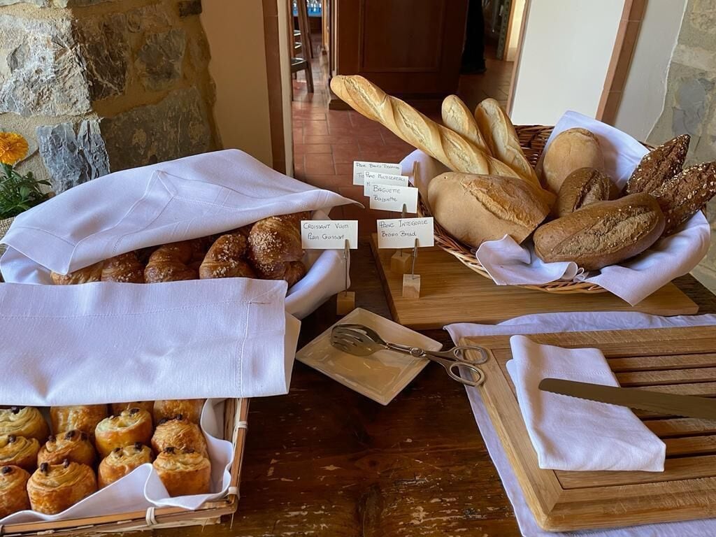 A variety of breads and pastries displayed on a wooden table with labels.