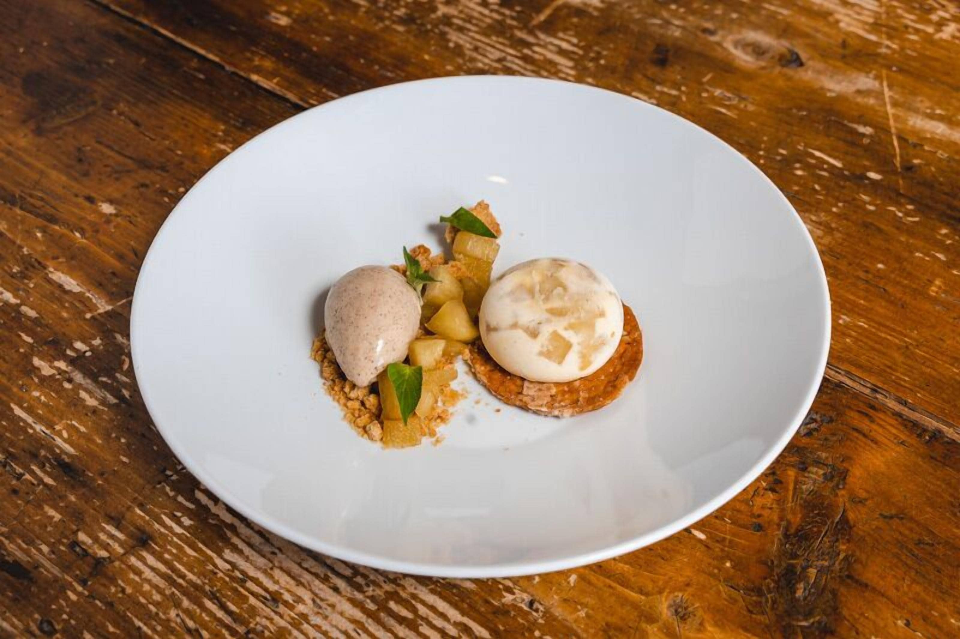 Un plato blanco con dos postres sobre una mesa de madera.