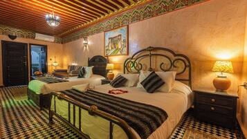 Habitación de hotel con suelo a cuadros, una cama con manta a rayas, dos mesitas de noche con lámparas y un cuadro en la pared.