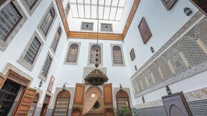 Une cour ornée de motifs complexes en mosaïque et dotée de portes en bois.
