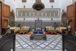 A traditional Moroccan interior with a fountain, patterned tiles, and ornate furniture. - Riad Ghita (Fes)