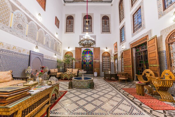A traditional Moroccan interior with ornate tile work, a central fountain, and a chandelier. - Riad Ghita (Fes)