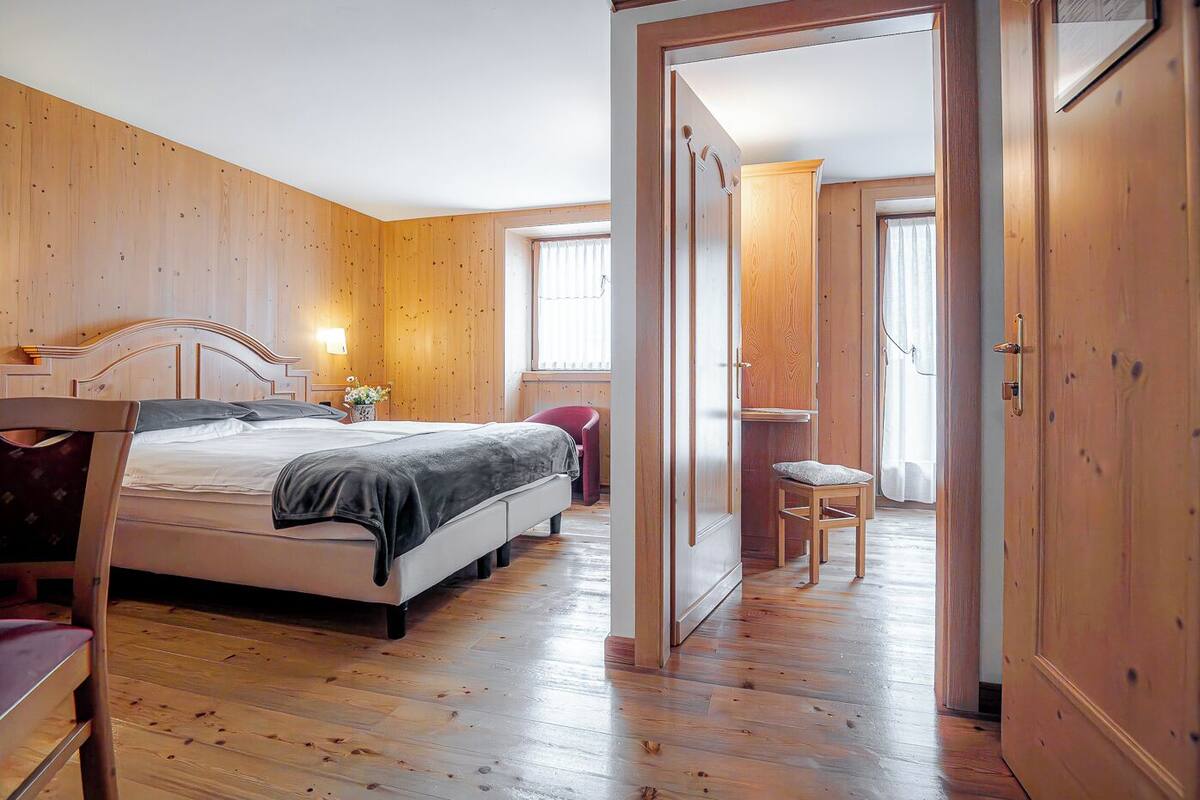 Un dormitorio con paneles de madera, una cama, una mesita de noche y una silla.