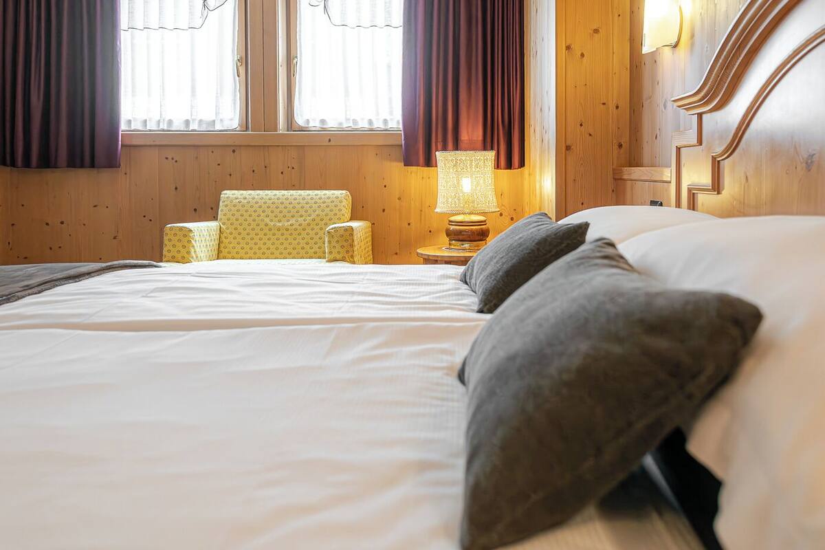 Una habitación de hotel con una cama grande, una silla, una mesita de noche y una lámpara.