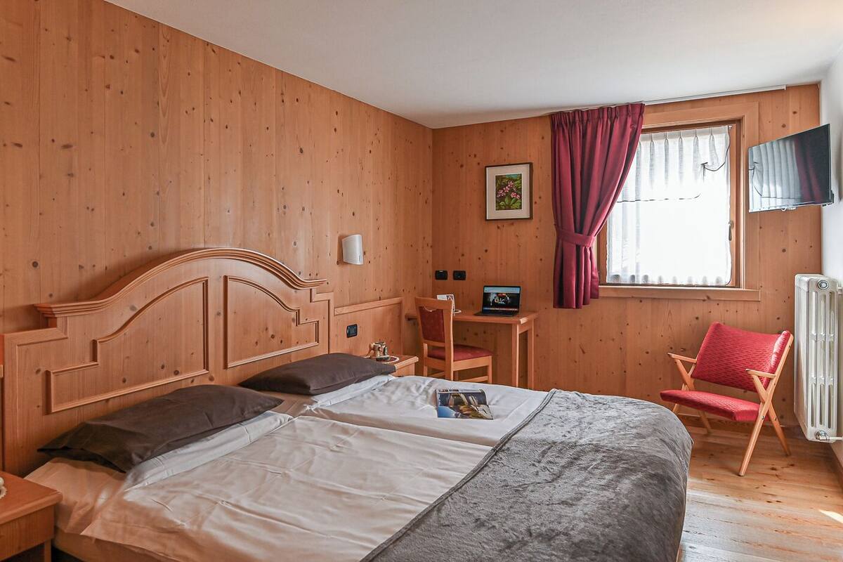 Una habitación de madera con una cama, un escritorio y una silla.