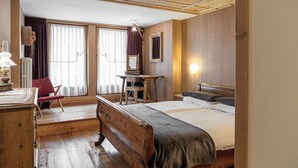 A wooden room with a bed, a desk, a chair, and a window with curtains. - Hotel Pedranzini (Valfurva)