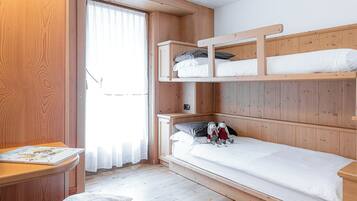 Camera con letto a castello in legno, una scrivania e una finestra.