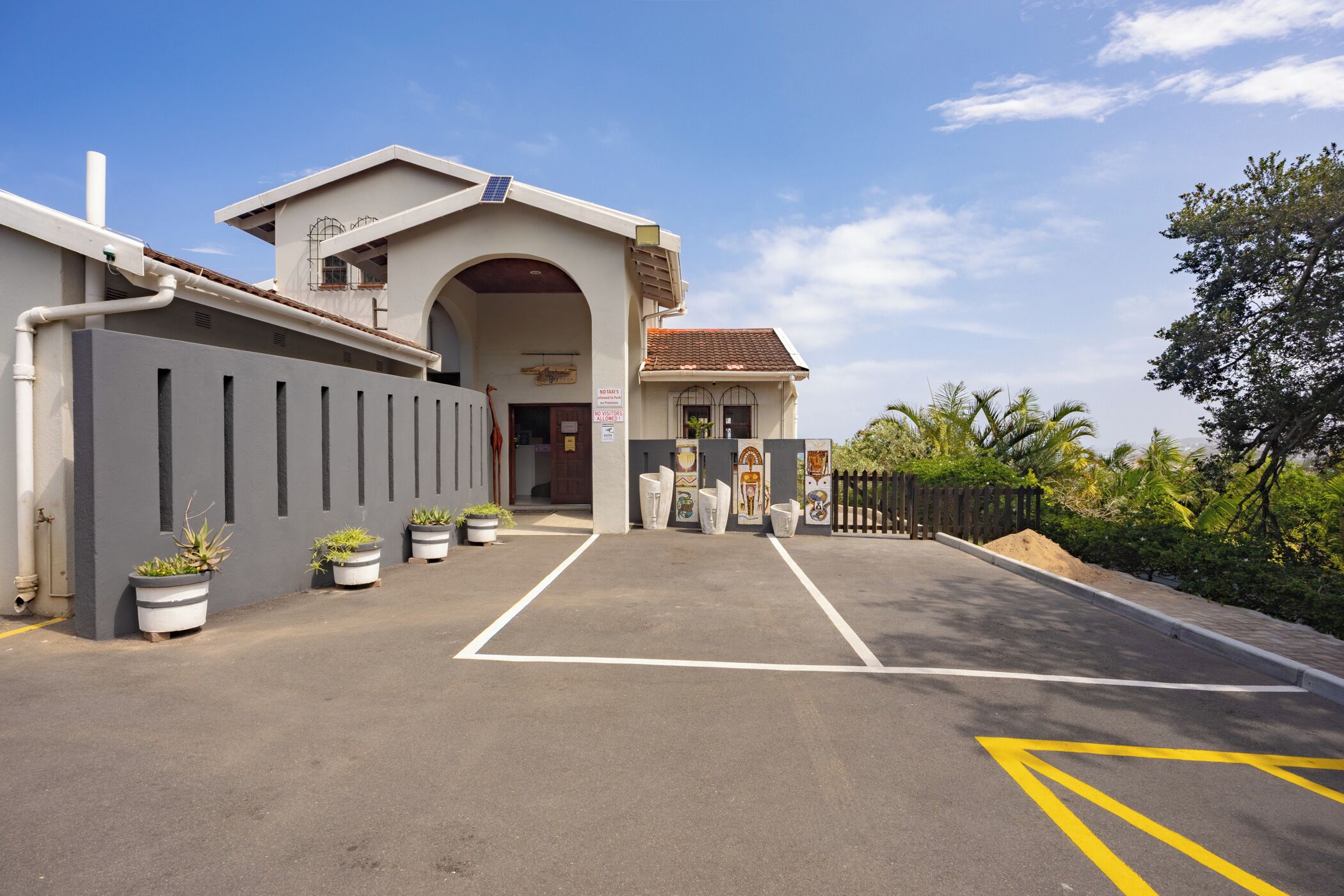 A building with a large entrance, potted plants, and a clear sky.