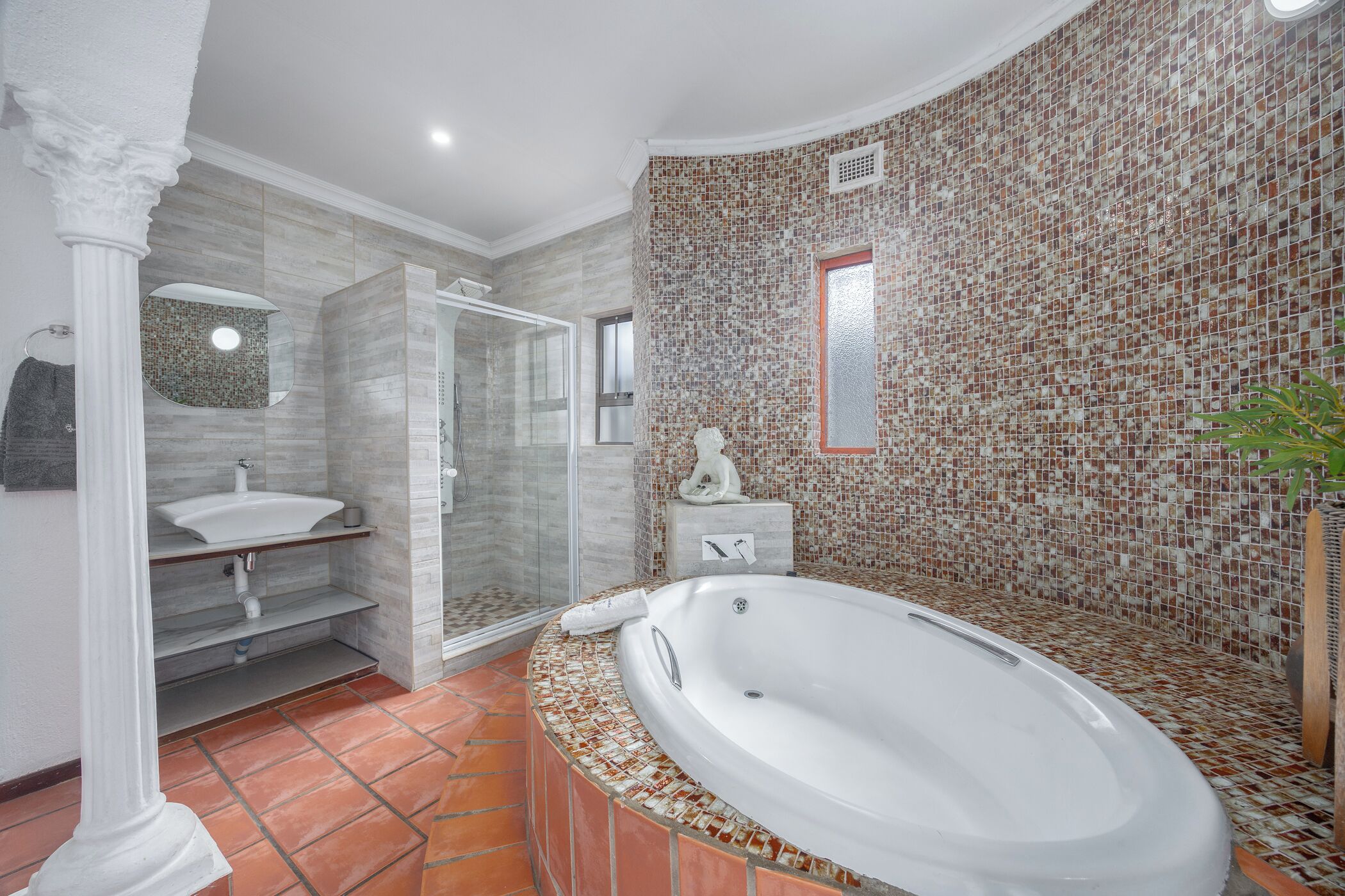 A bathroom with a large bathtub, a shower, and a sink.