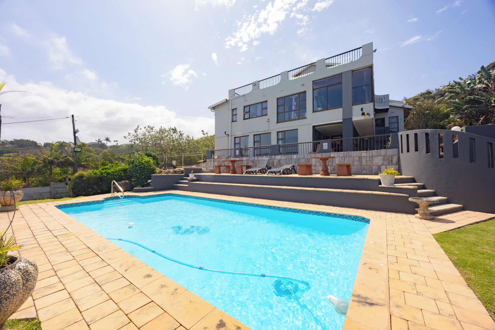Une maison moderne à deux étages, dotée d’une piscine, d’un chemin en pierre et d’un jardin.
