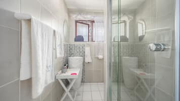 A compact bathroom with a shower, a toilet, and a sink.