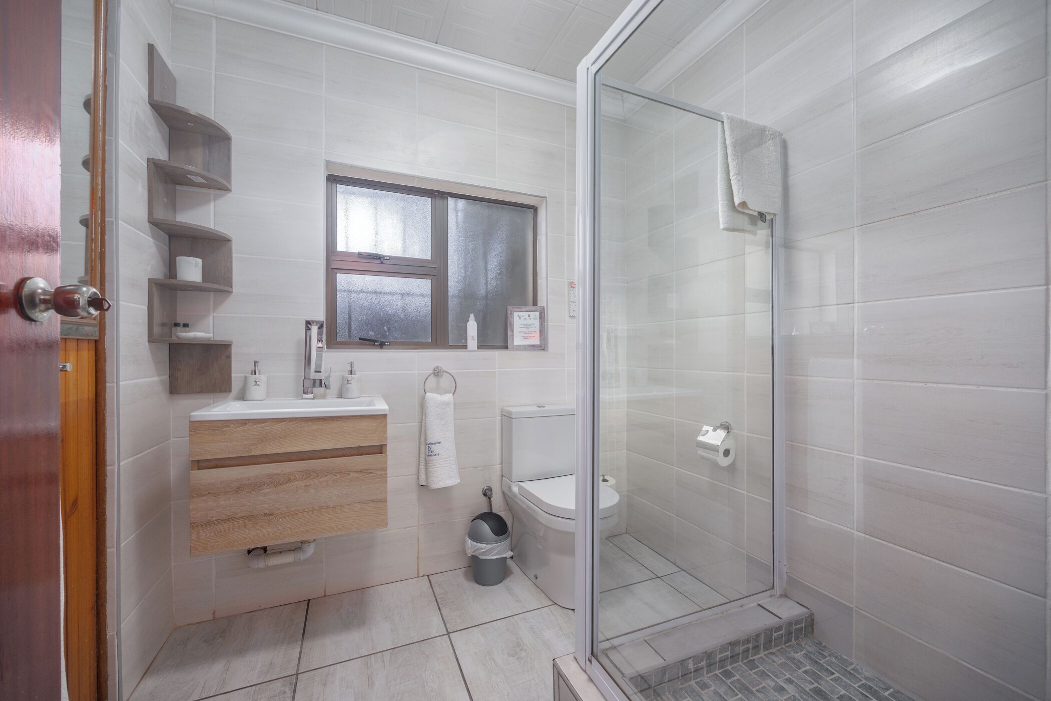 Une salle de bain moderne avec une douche à parois de verre, un meuble-lavabo en bois et des toilettes.