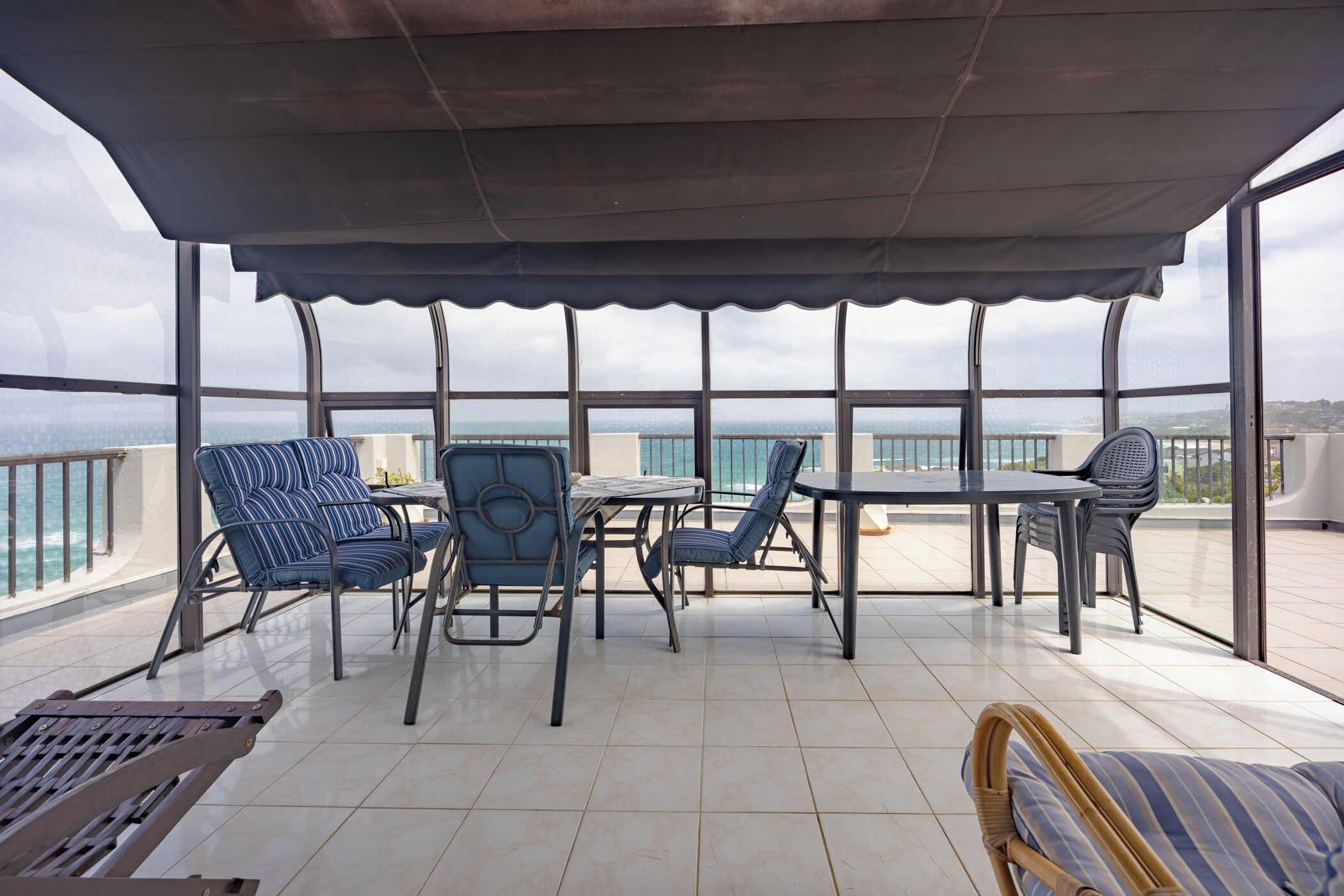 A covered outdoor seating area with a view of the sea.