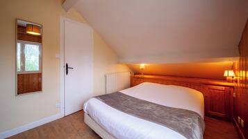 A bedroom with a large bed, wooden walls, a sloped ceiling, and a window.