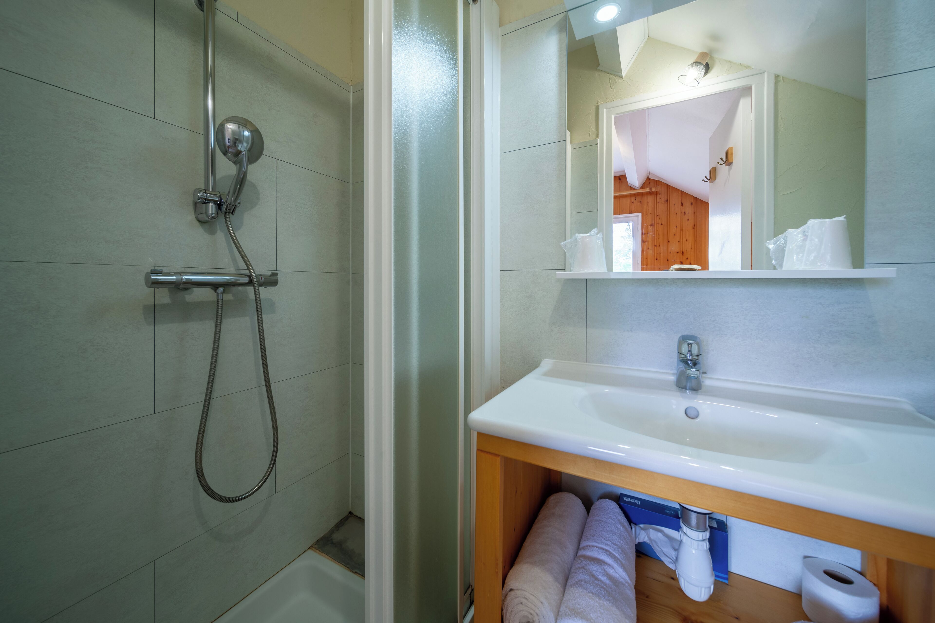 Un bagno con doccia, lavandino e specchio.