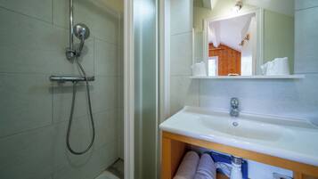 Un bagno con doccia, lavandino e specchio.