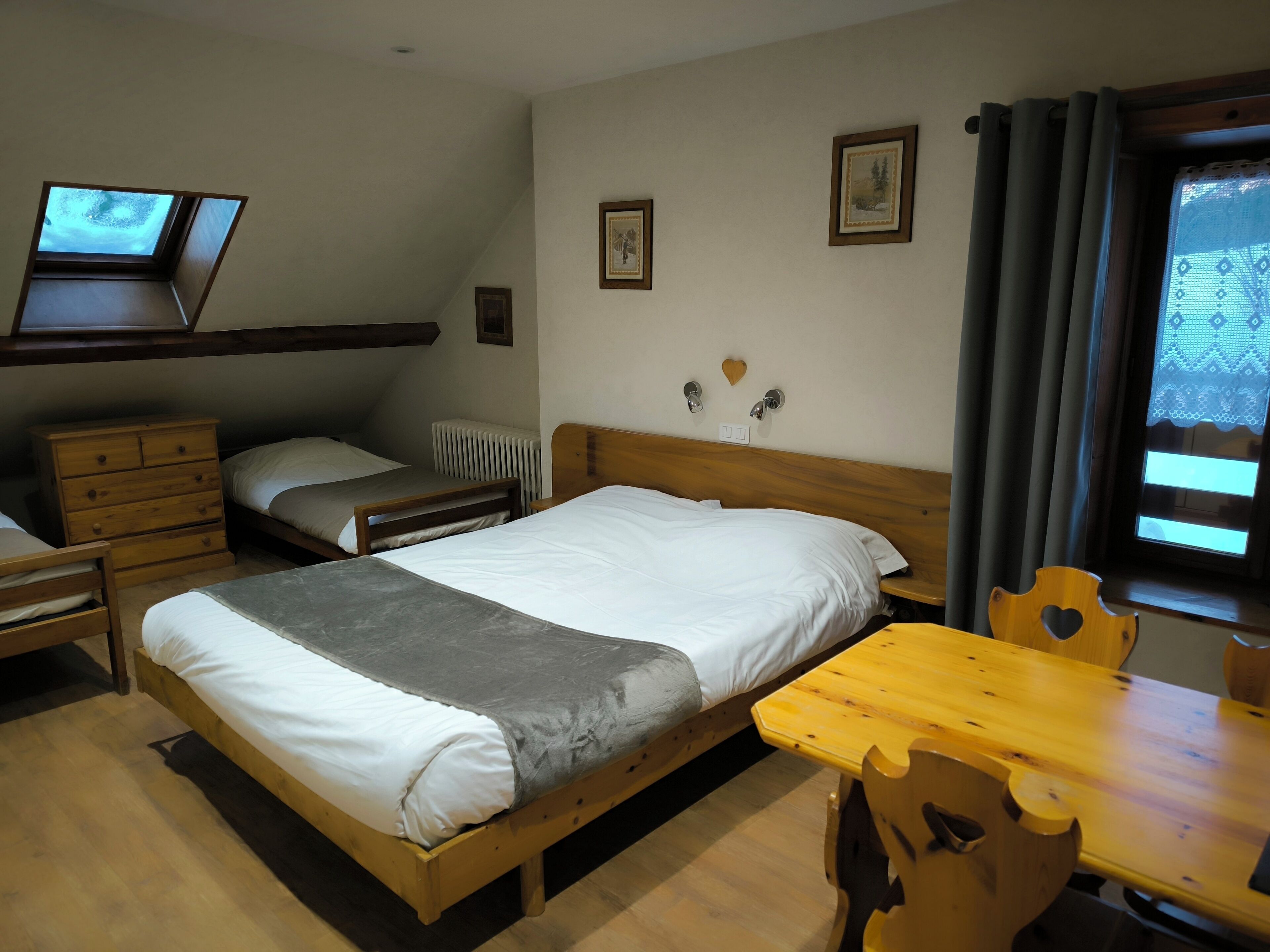 Un dormitorio con una cama grande, un aparador de madera, un escritorio y una ventana con cortinas.