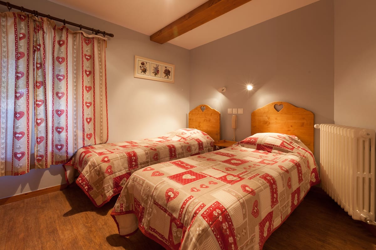 A bedroom with two single beds, a wooden headboard, a radiator, and a wall-mounted picture.