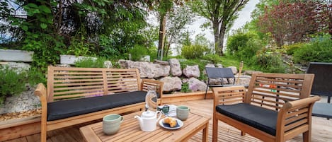 Un espacio al aire libre con mobiliario de madera y una mesa dispuesta para dos personas.