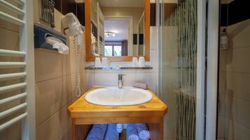 Une salle de bain avec un meuble-lavabo en bois, un lavabo blanc, un miroir et un porte-serviettes avec des serviettes.