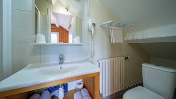 Un baño con lavamanos blanco, espejo, secador de pelo, toallero y retrete.