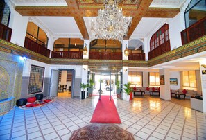 A spacious lobby with a red carpet, ornate ceiling, and traditional decor. - Hôtel Nouzha La perle du tourisme (Fes)