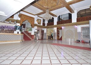 A spacious lobby with a tiled floor, a grand chandelier, and intricate wall designs. - Hôtel Nouzha La perle du tourisme (Fes)