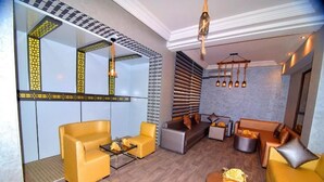 A modern living room with yellow sofas, a coffee table, and a fireplace. - Hôtel Nouzha La perle du tourisme (Fes)