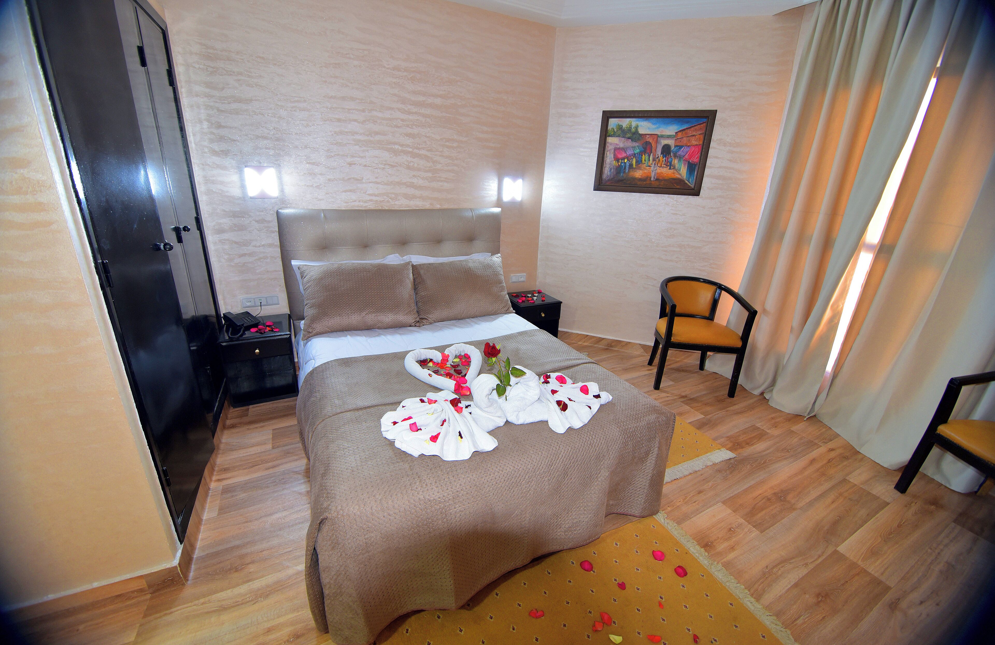 Quarto de hotel bem arrumado com uma cama, uma cadeira, uma mesa de cabeceira e um quadro na parede.