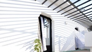 A white building with a black door and a small plant by the entrance. - Hôtel Nouzha La perle du tourisme (Fes)