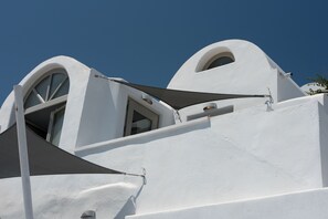 A white building with arched windows and a triangular awning. - La Perla Villas and Suites - Adults Only (Santorini)
