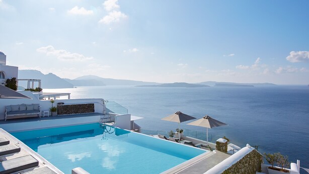 A clear blue sky, a swimming pool, and a view of the sea. - La Perla Villas and Suites - Adults Only (Santorini)
