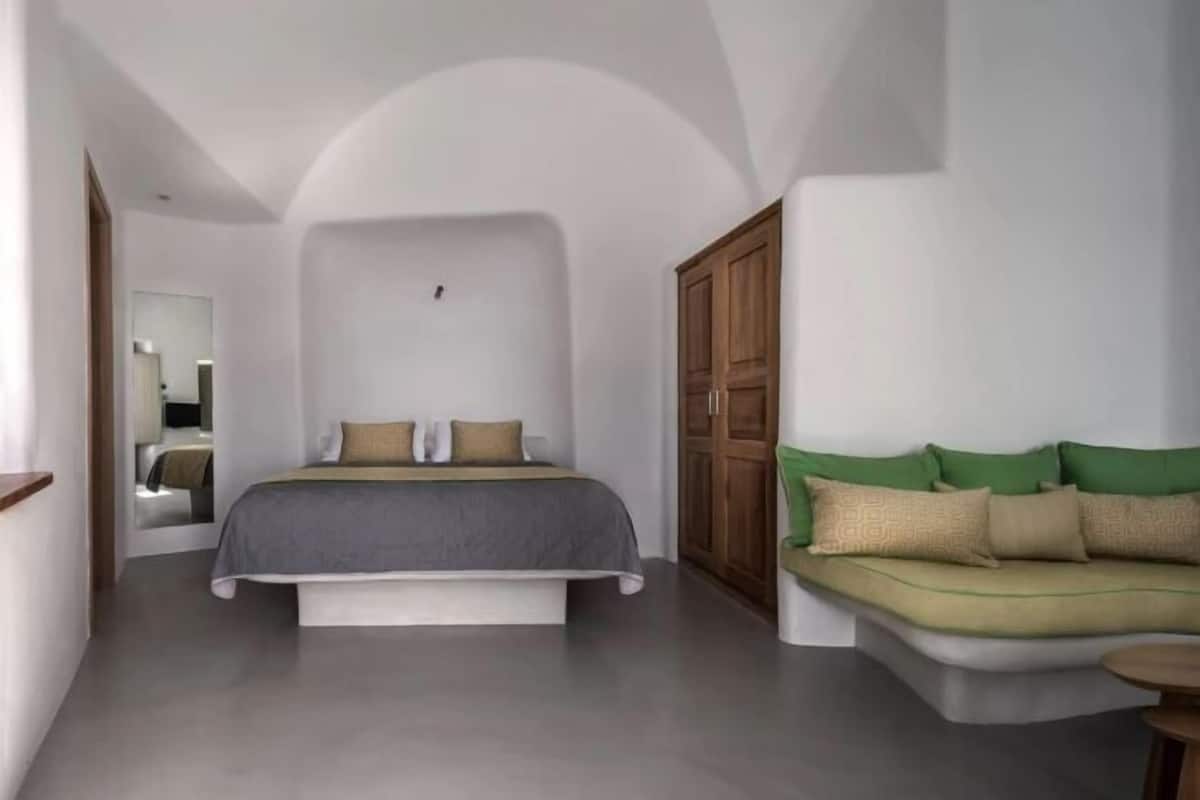 Een slaapkamer met een bed, een bank, een kledingkast en een spiegel.