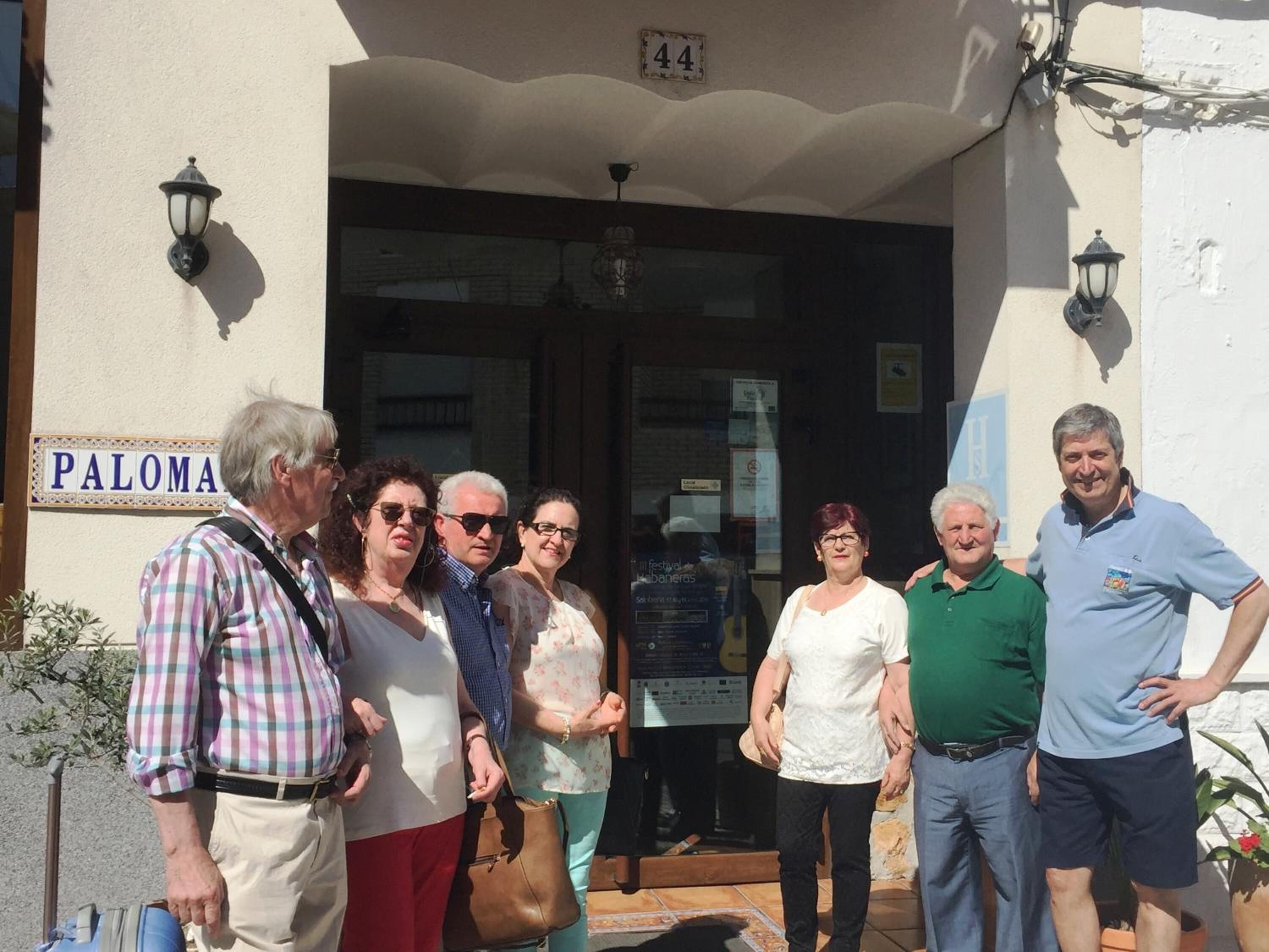 Un grup de persones al costat d'un edifici amb un rètol que diu "PALOMA".