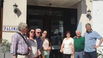 Een groep mensen staat buiten een gebouw met een bord waarop