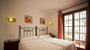 A double bed with a metal frame, a bedside table, a nightstand, and two wall-mounted light fixtures. - Hostal Palomares (Salobreña)