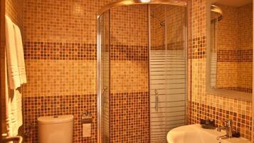 Un baño con ducha envuelta en vidrio, inodoro y lavamanos.