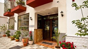 A hotel entrance with a tiled patio, potted plants, and a sign reading "PALOMARES". - Hostal Palomares (Salobreña)