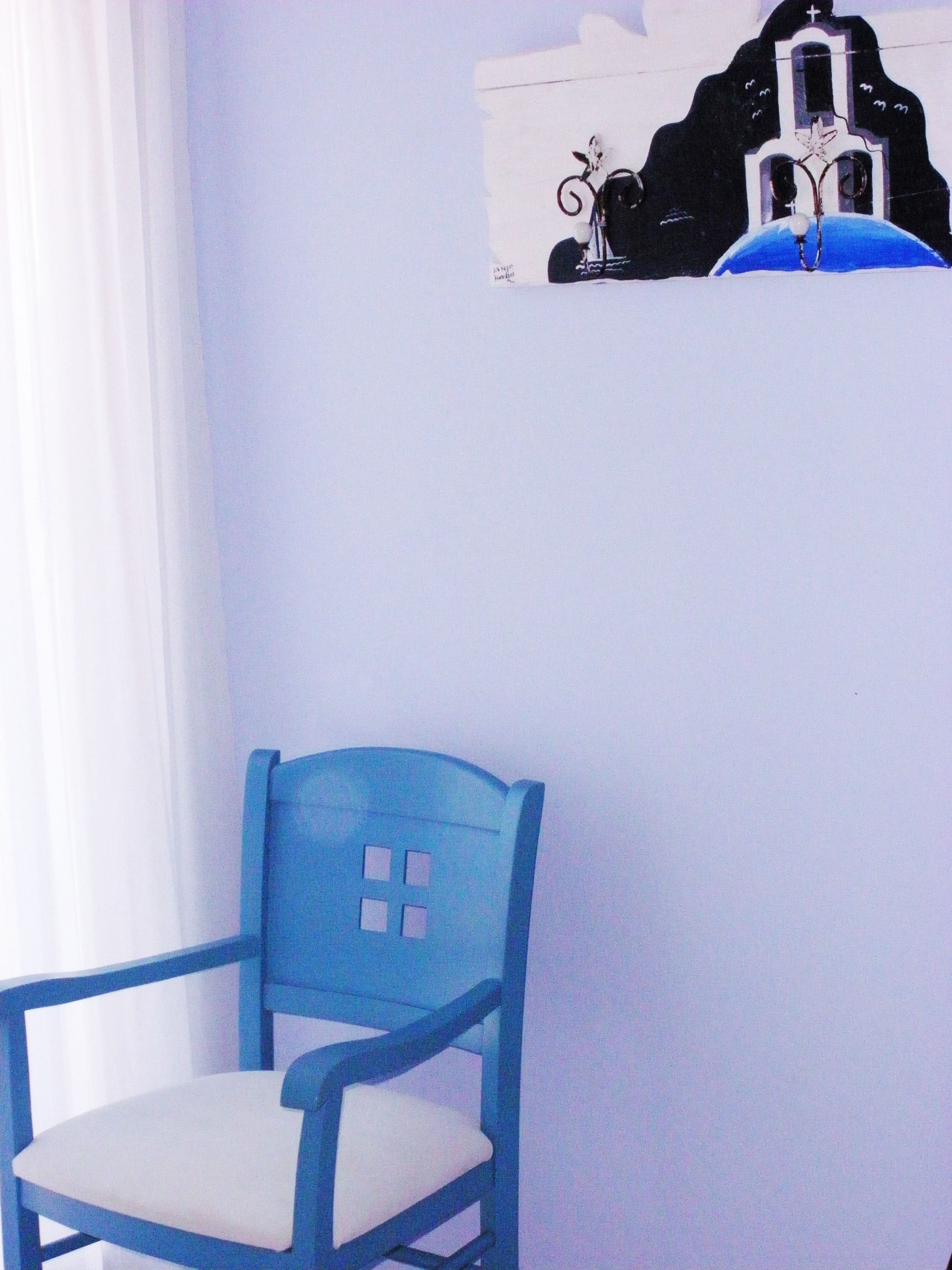 A blue chair with a white cushion in a room with a white wall and a small black and white building decoration.